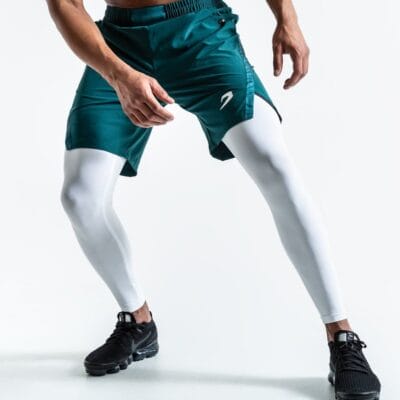 A man dons Pep Shorts (2-In-1 Training Tights) in green and white, striking a pose for a photo.