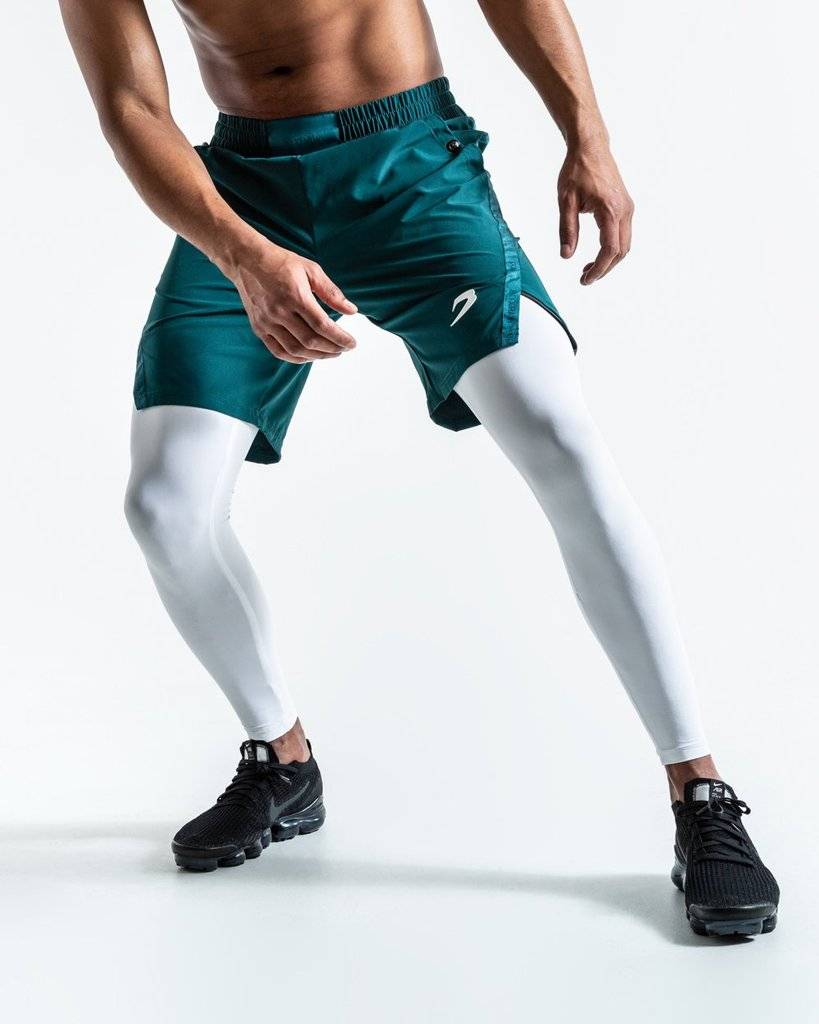 A man dons Pep Shorts (2-In-1 Training Tights) in green and white, striking a pose for a photo.