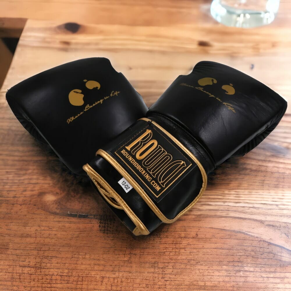 A pair of 12 oz black boxing gloves on a wooden table.