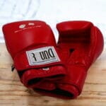 A pair of black boxing gloves on a wooden table.