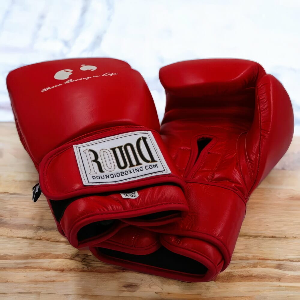 A pair of black boxing gloves on a wooden table.