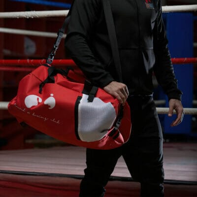 A man holding a red duffel bag in a boxing ring during Round 10 of the match.